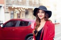 Smiling girl in black hat on red car background