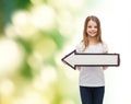 Smiling girl with blank arrow pointing left Royalty Free Stock Photo