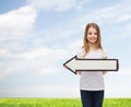 Smiling girl with blank arrow pointing left Royalty Free Stock Photo