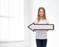 Smiling girl with blank arrow pointing left Royalty Free Stock Photo