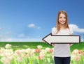 Smiling girl with blank arrow pointing left Royalty Free Stock Photo