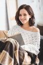 Smiling girl in blanket reading book on sofa at home Royalty Free Stock Photo