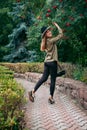 Smiling girl with blond long hair, in black leggings, a tank top, a beige jacket and a hat Royalty Free Stock Photo