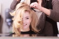 Smiling girl with blond wavy hair by hairdresser in beauty salon Royalty Free Stock Photo