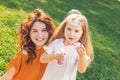 Smiling girl blowing soap bubbles in the park with mother looking at the camera Royalty Free Stock Photo