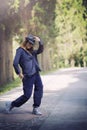 Smiling girl in blue clothes and a hat in a dancing pose in a park alley Royalty Free Stock Photo