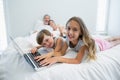 Smiling girl and boy using laptop on bed in bedroom at home Royalty Free Stock Photo