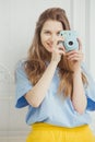 Smiling girl in casual cloth makes photo by portative camera Royalty Free Stock Photo