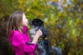 A smiling girl of Caucasian appearance holds a small papillon dog in her arms. Walk in the park