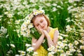 Smiling girl on a chamomile field in spring. Enjoys the scent of daisies with his eyes closed. With a bouquet of flowers and a Royalty Free Stock Photo