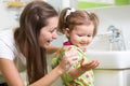 Smiling girl child and her mom washing hands and Royalty Free Stock Photo