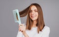 Smiling girl combing hair. Beautiful young woman holding comb straightened hair. Attractive smiling woman portrait with