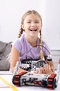 Smiling girl creating electronic robot at school