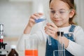 Smiling girl doing home science project, pouring liquid into a flask Royalty Free Stock Photo