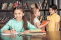 Smiling girl doing homework with classmates talking behind Royalty Free Stock Photo