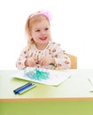 Smiling girl draws markers on a sheet of paper