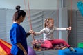 Smiling girl enjoying sensory therapy on a swing when physiotherapist helps her