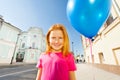 Smiling girl with flying balloon stands on street Royalty Free Stock Photo