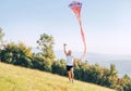 Smiling girl with a flying colorful kite running on a high green grass meadow in the mountain fields. Happy childhood moments or Royalty Free Stock Photo