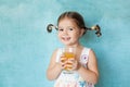 Smiling girl with funny pigtails with glass of juice Royalty Free Stock Photo