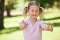 Smiling girl gesturing thumbs up at park Royalty Free Stock Photo