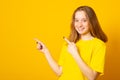 Smiling girl gives advice promots product, wears red dress, indicates at advertisement, introduces promo with pleased expression