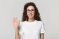Smiling girl in glasses looking at camera wave hand studioshot Royalty Free Stock Photo