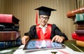 Smiling girl in graduation cap using digital tablet at library Royalty Free Stock Photo