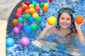 Girl having fun In garden paddling pool with color balls Royalty Free Stock Photo