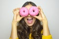 Smiling girl having fun with sweets isolated on gray background. Attractive young woman with long hair posing with doughnuts Royalty Free Stock Photo