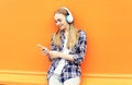 Smiling girl in headphones listens to music and using smartphone Royalty Free Stock Photo