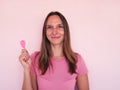 Smiling girl with heard shape lollipop smile to camera at pink wall at background. Valentines day