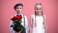 Smiling girl and her little boyfriend holding red flowers, looking to camera