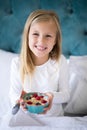 Smiling girl holding breakfast cereal on bed Royalty Free Stock Photo