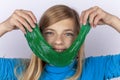Smiling girl holding a green slime toy in front of her face Royalty Free Stock Photo