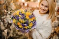 Smiling girl holding a little bouquet with purple and white flowers wrapped in gift paper Royalty Free Stock Photo