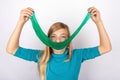 Smiling girl holding a long green slime toy in front of her face Royalty Free Stock Photo