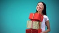 Smiling girl holding many giftboxes, fest presents, standing on blue background