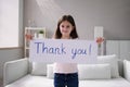 Smiling girl holding thank you sign against white Royalty Free Stock Photo