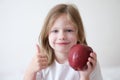 Smiling girl holding thumbs up and holding ripe apple Royalty Free Stock Photo