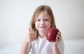 Smiling girl holding thumbs up and holding ripe apple Royalty Free Stock Photo