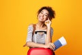 Smiling Girl Holding Tickets Sitting With Suitcase, Studio Shot