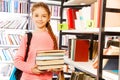 Smiling girl holds books near shelf in library Royalty Free Stock Photo