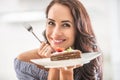 Smiling girl holds a sweet treat in a form of layered cake in her hand