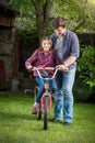 Smiling girl learning how to ride a bicycle with her father at p Royalty Free Stock Photo
