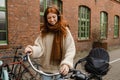 Smiling girl listening music with headphones while standing with bicycle at street Royalty Free Stock Photo