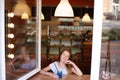 Smiling girl looking out of the cafe window nad drinking blue beverage