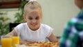 Smiling girl looking at pizza and choosing best slice, family food traditions