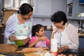 Smiling girl with mother and grandmother preparing food in kitchen