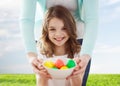 Smiling girl and mother holding colored eggs